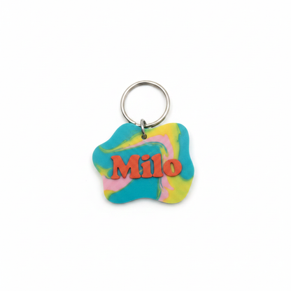Colorful personalized wavy pet ID tag with metal ring on a white background